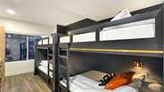 The C suite boats 2 custom built-in queen over queen bunk beds with 2 65" TVs, a microwave, and a full bathroom.