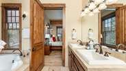 Primary suite bathroom with double vanity, walk-in shower, and jet tub