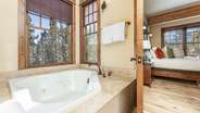 Primary suite bathroom with double vanity, walk-in shower, and jet tub