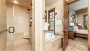 Primary suite bathroom with double vanity, walk-in shower, and jet tub